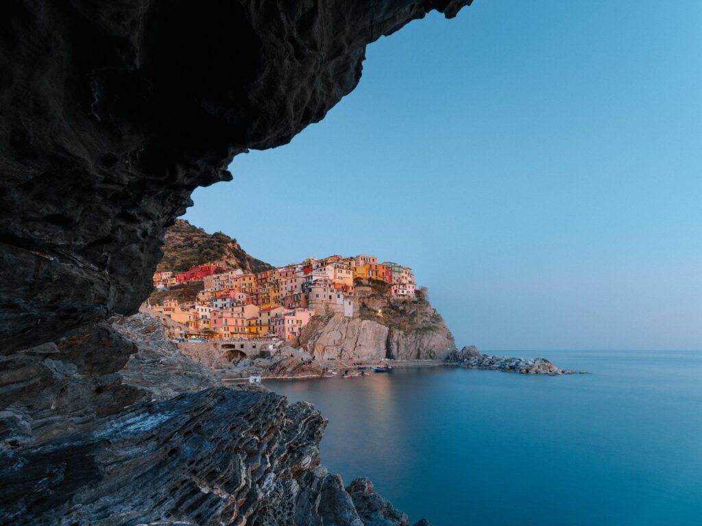 pexels photo 4254553 4254553 Stunning view of Manarola's colorful cliffs and calm sea under a blue evening sky.